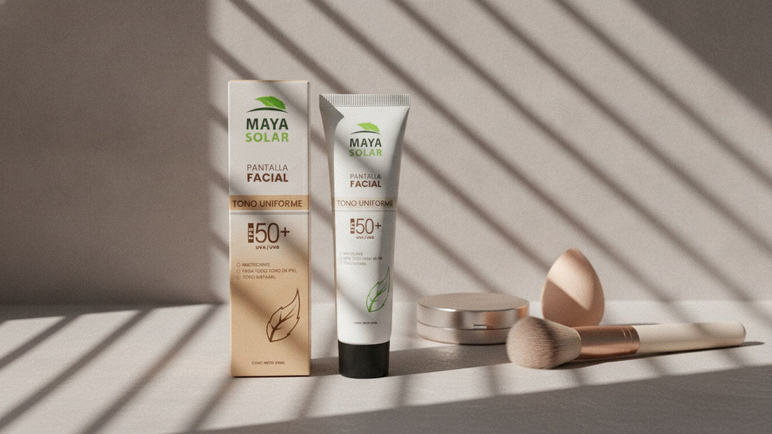 Protector solar facial tono uniforme de Maya Solar, de pie sobre un tocador junto a una brocha y una esponja de maquillaje