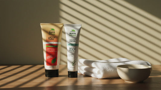 Bloqueador solar en crema FPS 50+ de 204 ml y protector solar facial piel sensible FPS 50+ de Maya Solar de pie sobre una mesa de madera, junto a una toalla blanca doblada y un tazón de cerámica, con sombras de persiana sobre la pared